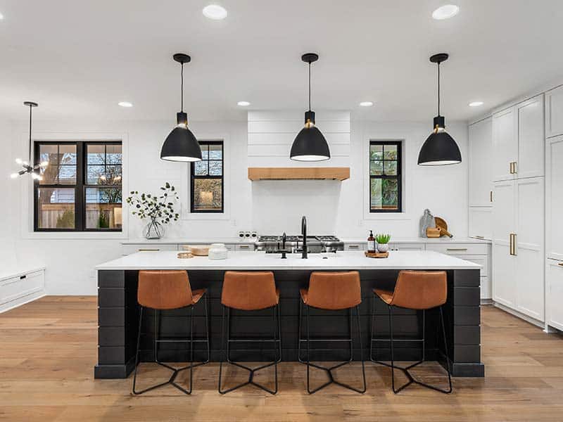 Bright modern kitchen with black island and warm brown barstools, ideal for kitchen remodeling.